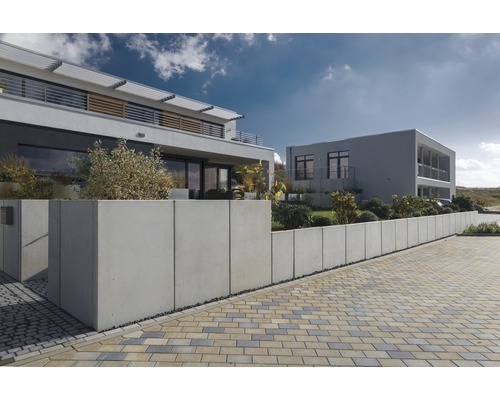 Außenaufnahme von zwei modernen Häusern mit Betonmauer und Pflastersteinen