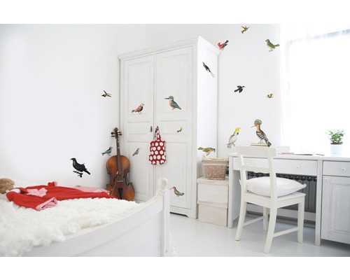 Helles Zimmer mit Bett, Schrank, Schreibtisch und Wandtattoo mit Vogelmotiven.