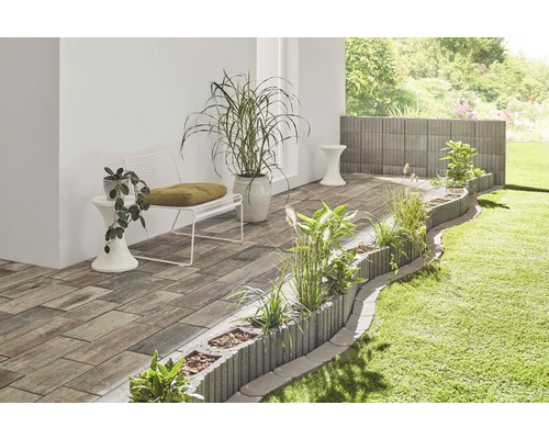 Gartenszene mit Pflastersteinen, Pflanzsteinen, Bank und Pflanzen