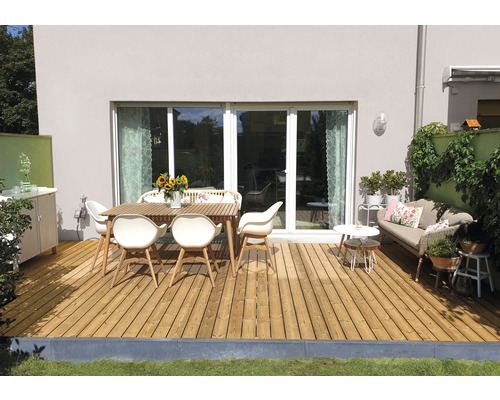 Terrasse mit Holzboden, Gartentisch und Stühlen vor einem Haus