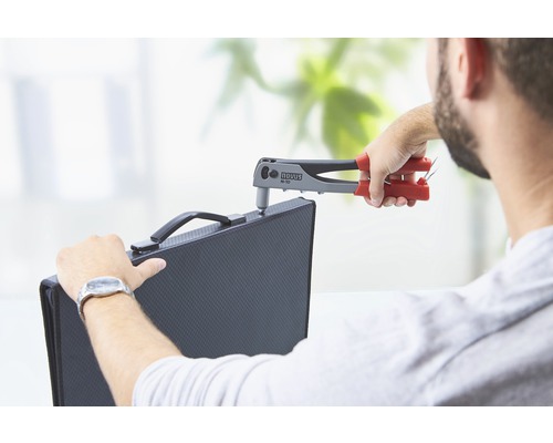 Eine Person befestigt ein Werkstück mit einer Nietzange der Marke Novus.