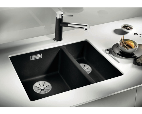 Schwarze Doppelspüle aus Verbundwerkstoff mit Wasserhahn auf einer weißen Arbeitsplatte