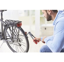 Mann befestigt Fahrradrücklicht mit einer Blindnietzange