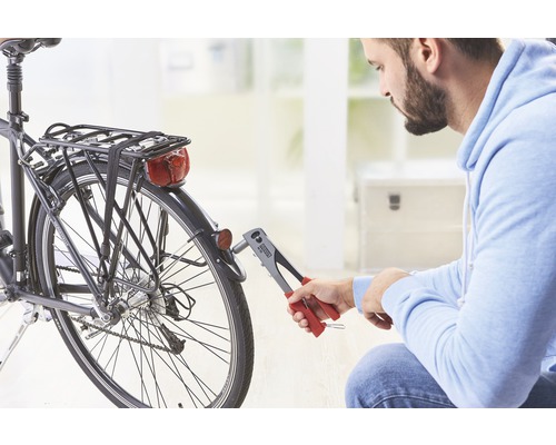 Mann befestigt Fahrradrücklicht mit einer Blindnietzange