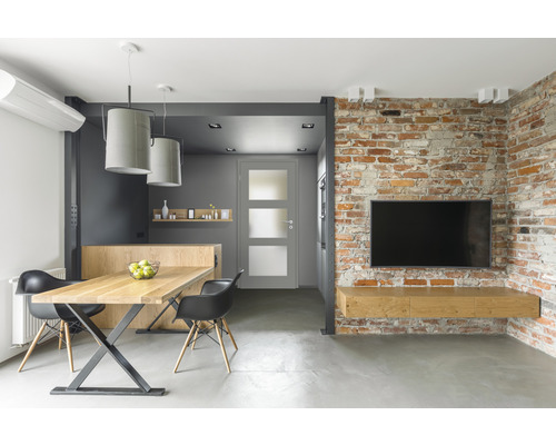 Modernes Wohnzimmer mit Esstisch, Stühlen, Tür und Fernseher an Ziegelwand
