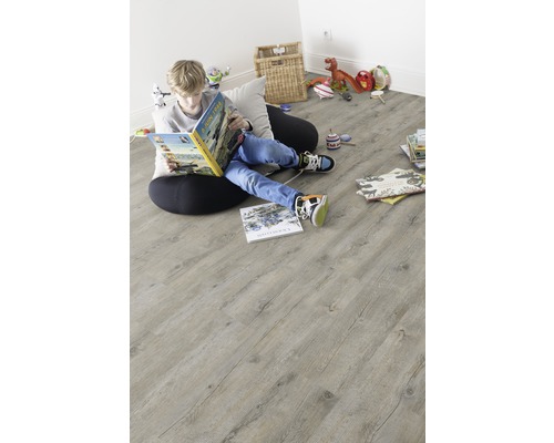 Ein Junge liest ein Buch auf einem hellen Holzboden im Kinderzimmer.