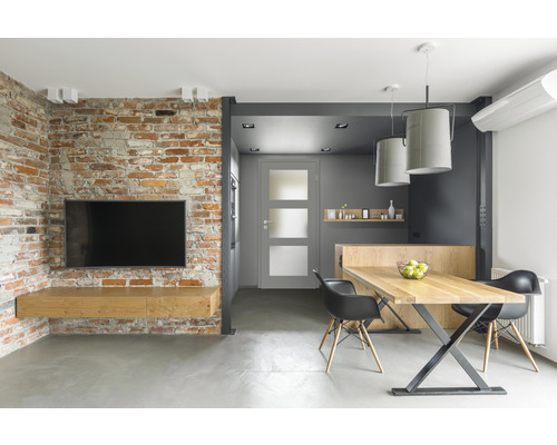 Heller Wohnraum mit Ziegelwand, Fernseher, Tisch und Stühlen