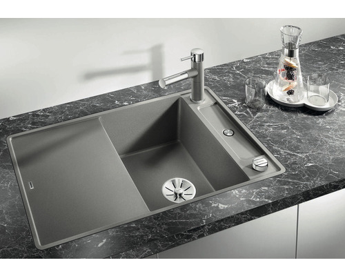 Spüle aus Granit mit Abtropffläche und Armatur auf einer Arbeitsplatte.