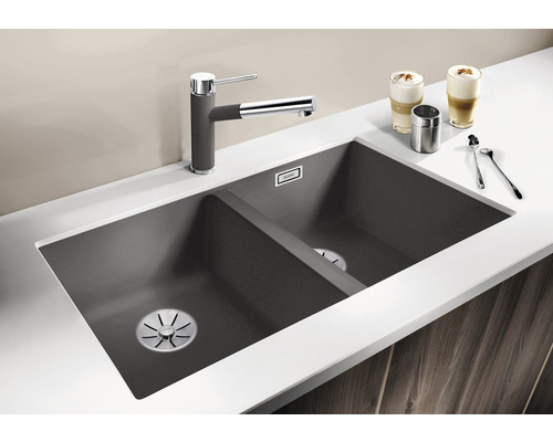 Spüle mit zwei Becken, Armatur und Küchenutensilien auf einer Arbeitsfläche.