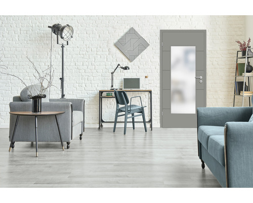 Wohnzimmer mit Tür mit Glaseinsatz, Sofa, Sessel und Schreibtisch