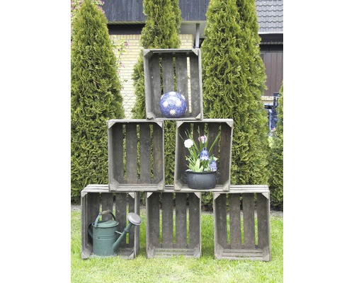 Dekorative Holzsteigen mit Blumenschmuck und Gießkanne im Garten