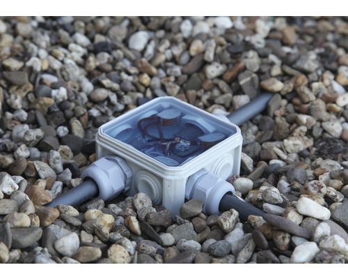 Abzweigdose mit Kabeln im Kies