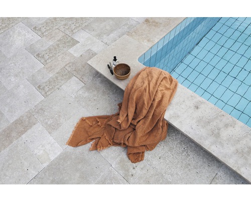 Ein Poolbereich mit Steinboden, einem Handtuch und Pflegeprodukten.