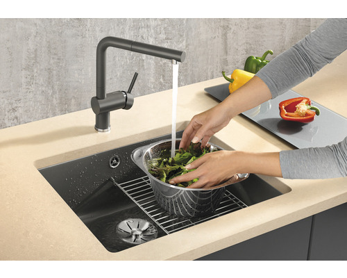 Person wäscht Salat in einem Spülbecken mit Wasserhahn.