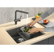 Frau wäscht Salat in einem Küchenspülbecken mit Wasserhahn