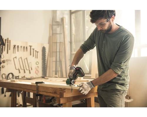 Handwerker sägt Holz mit einer Akku-Säbelsäge in einer Werkstatt.