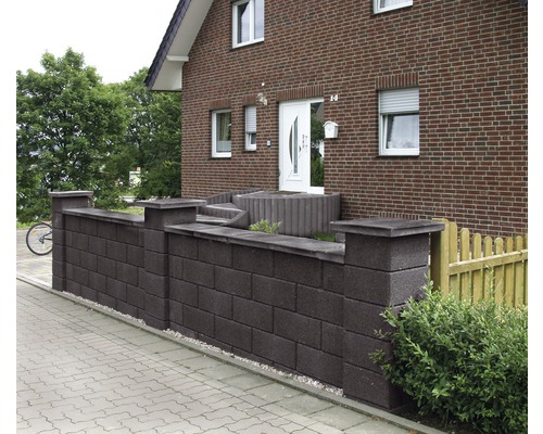 Betonsteinmauer vor einem Wohnhaus mit Pflastersteinen
