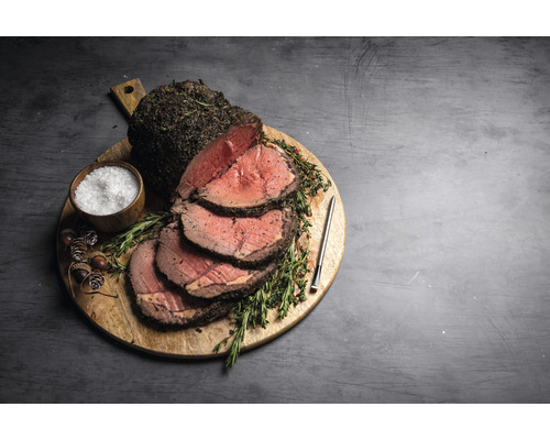Rinderbraten auf Holzbrett mit Salz, Kräutern und Fleischthermometer