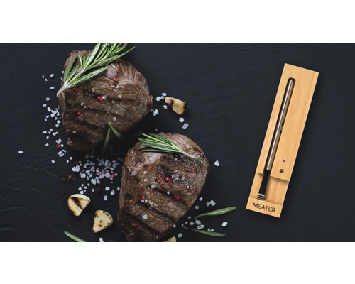 Zwei Steaks mit Kräutern und Gewürzen und ein Fleischthermometer der Marke Meater