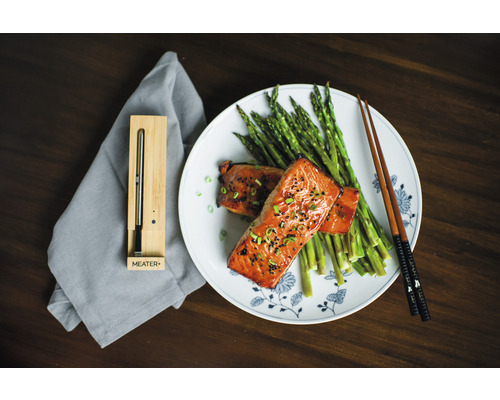 Ein Teller mit Lachs, Spargel und Essstäbchen neben einem intelligenten Fleischthermometer