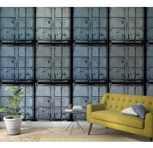 Raumansicht mit Containermotivtapete, gelbem Sofa und Zimmerpflanze