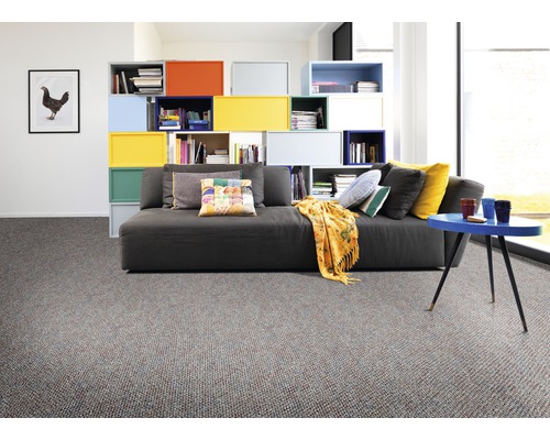 Wohnzimmer mit Sofa, bunten Regalen und Teppichboden