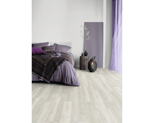 Schlafzimmer mit hellem Holzboden, Bett, Nachttisch und Dekorationen.