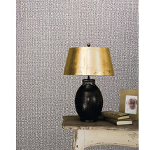 Szene mit Textiltapete, Lampe und Dekoration auf einem Tisch