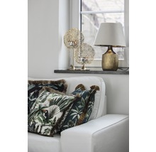 Dekoratives Wohnzimmer mit Sofa, Kissen mit Pflanzenmotiven, Tischleuchte und Windlichtern.