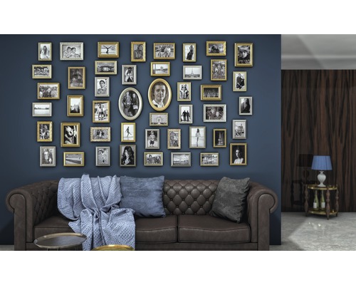 Wohnzimmer mit braunem Ledersofa, blauen Kissen und einer Wand voller Bilderrahmen