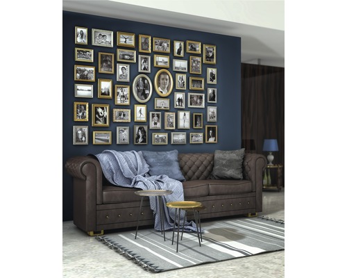 Wohnzimmer mit braunem Ledersofa, Couchtisch und einer Wand voller Bilderrahmen.