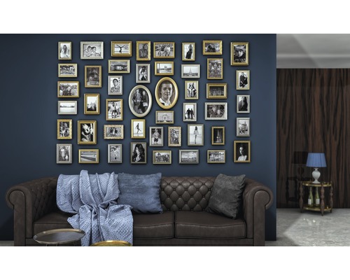 Wohnzimmer mit braunem Sofa, blauer Wand und vielen Bilderrahmen