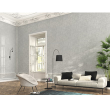 Wohnzimmer mit grauer Mustertapete, Sofa, Sessel und Zimmerpflanze