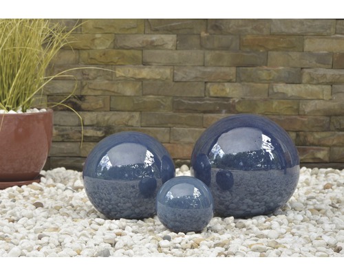 Drei blaue Gartenkugeln aus Keramik auf Kies