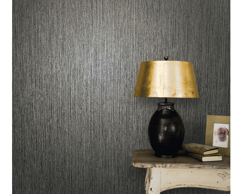 Nahaufnahme einer Wand mit Strukturtapete, einem Tisch und einer Tischlampe.