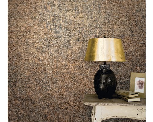 Nahaufnahme einer Wand mit einer strukturierten Tapete neben einem Tisch mit Lampe, Büchern und Fotorahmen.