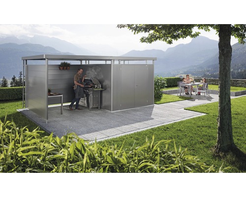 Überdachte Grillstelle mit grillendem Mann und Familie im Hintergrund