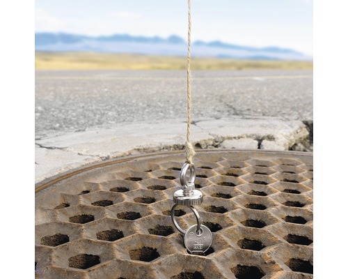 Schlüssel an einem Magneten, der an einem Seil über einem Gullydeckel befestigt ist