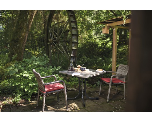 Gartenszene mit Tisch, Stühlen und Wassermühle im Hintergrund