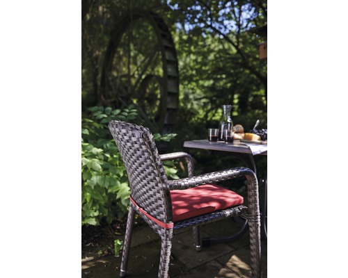 Szene mit Gartenstuhl, Tisch, Getränken und Speisen im Freien vor einem Wasserrad.