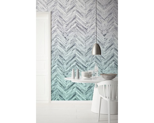 Ein Esszimmer mit einer Wandtapete im Fischgrätenmuster, einem runden Tisch und Stühlen.