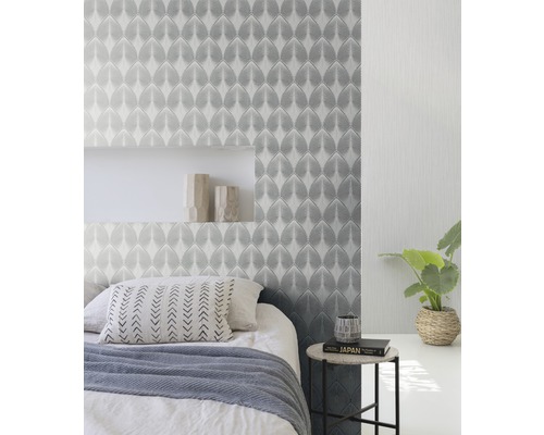 Schlafzimmer mit gemusterter Tapete, Bett und Beistelltisch.