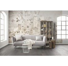 Wohnzimmer mit Sofa, Regal, Tisch und Dekor vor einer Wand mit Zeitungsmuster