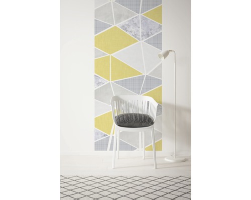 Dekorative Tapete mit geometrischem Dreiecksmuster, weißer Stuhl mit Kissen und Stehlampe auf einem gemusterten Teppich.