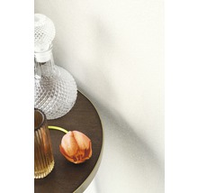 Dekorative Tapete an einer Wand neben einem Tisch mit Karaffe und Blume.