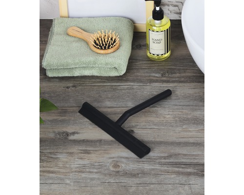 Schwarzer Duschabzieher auf einem Holztisch mit Handtuch, Haarbürste und Seife