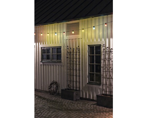 Außenansicht eines Hauses mit Fenster, Pflanzkästen und einer Lichterkette.