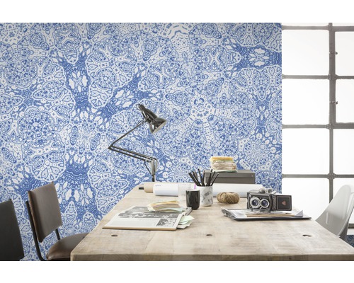 Arbeitszimmer mit blau gemusterter Tapete, Schreibtisch, Lampe und Stuhl