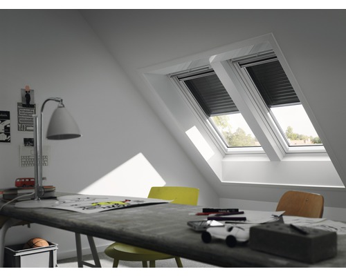 Zwei Dachfenster mit Rollläden in einem Dachgeschosszimmer mit Schreibtisch