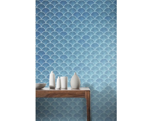 Szene mit einer blauen Tapete mit Fischschuppenmuster und einem Holztisch mit Dekoration